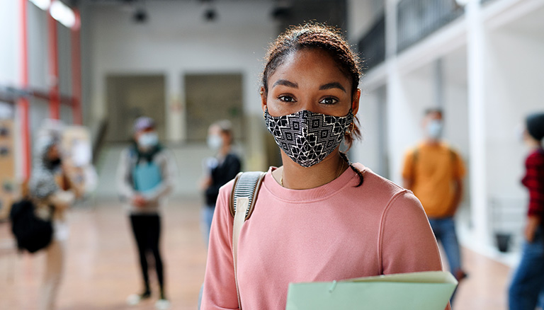 Portrait of african-american student with face mask back at college or university, coronavirus concept.